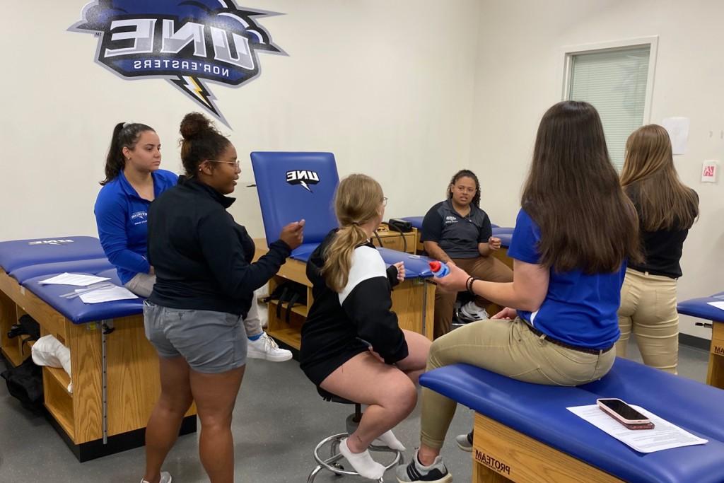 A group of graduate athletic training students practice rehabilitation techniques in the Alfond Forum 