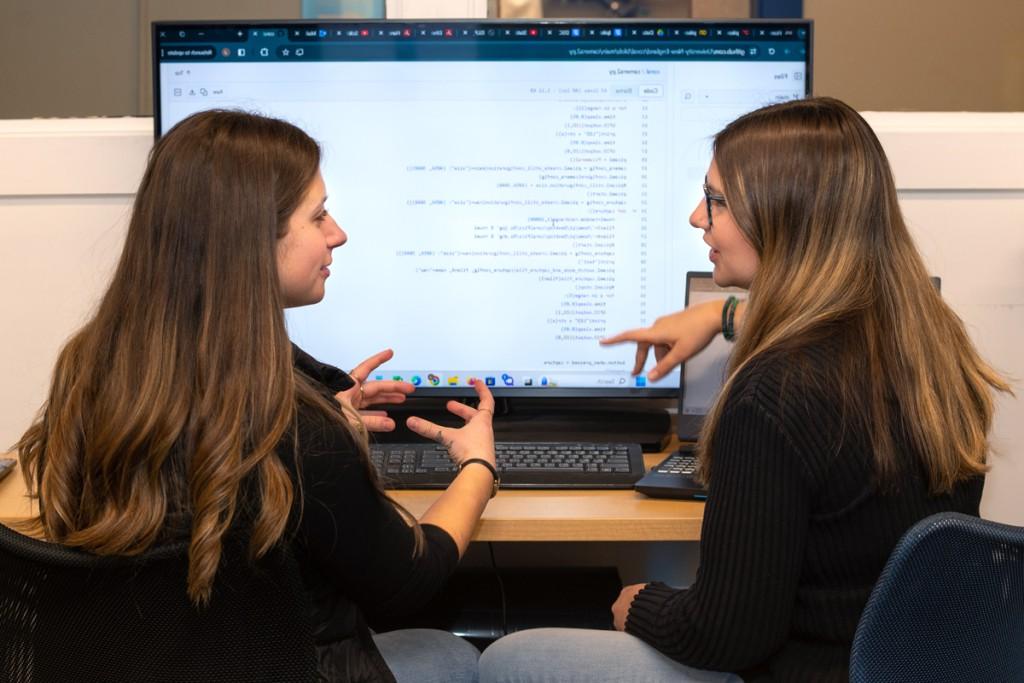 两个计算机科学专业的学生在显示器上复习计算机代码