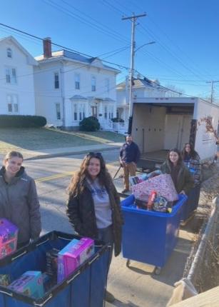 学生 和 volunteers load toys 和 gifts into a box truck