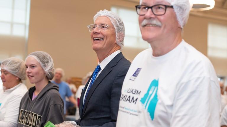 正规澳门赌场网络校长詹姆斯·赫伯特在缅因州的“膳食”活动中帮助打包食物时微笑着
