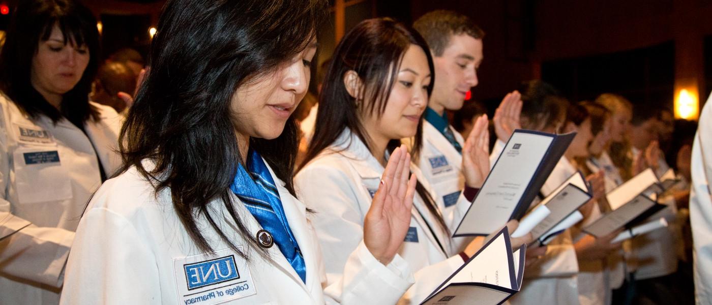 药学一年级的学生穿着白大褂站在那里，背诵着专业誓词 