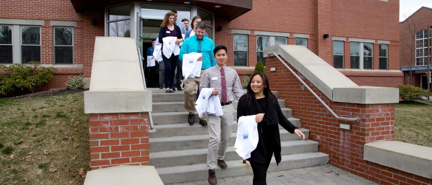 U N E College of Pharmacy students walk out of building with white coats