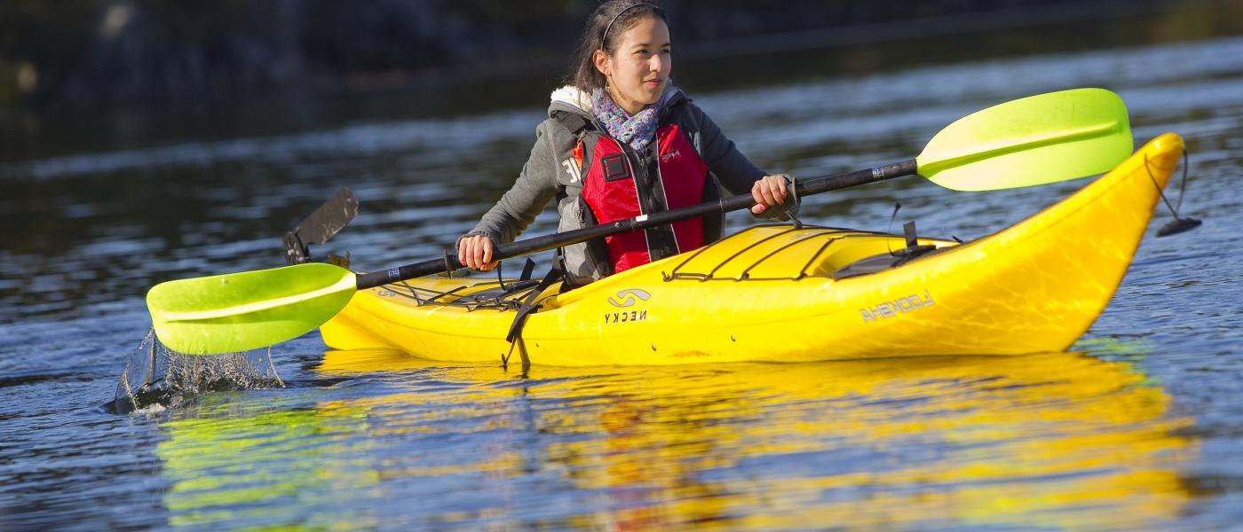 A U N E student paddles in a yellow kayak 