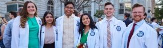 Six University of New England medical school students pose in their white coats