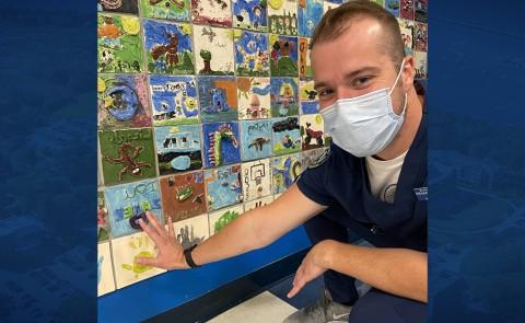 Male student touches wall art he made as a kid