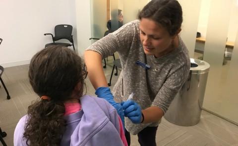 护理专业学生伊丽莎白·阿尔文正在给一位健康博览会的参观者注射流感疫苗